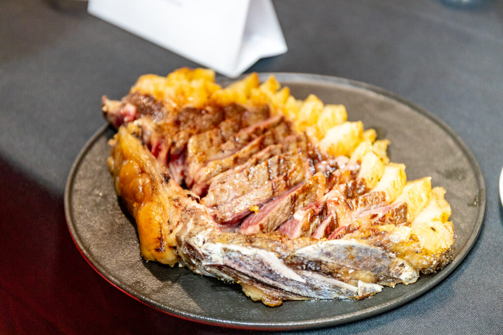 Sliced roast beef with crispy potatoes on a dark plate.